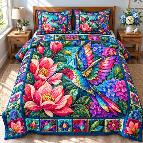 Hummingbird Floral Glow quilted bedding set, quilt and two pillow shams on a made bed