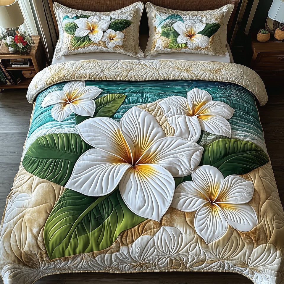 Island Plumera Paradise White Blooms On Sand quilted bedding set, quilt and two pillow shams on a made bed